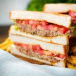 Canned tomato and sardine salad sandwich served with French fries.