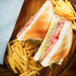 Overhead canned tomato and sardine salad sandwich served with French fries.