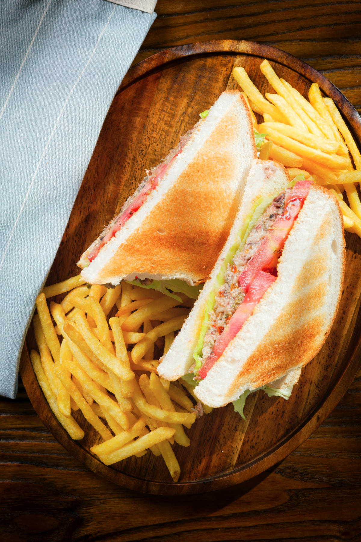 Overhead tomato and cannded sardine salad sandwich served with French fries.