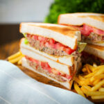 Tinned tomato and sardine salad sandwich on toasted bread served with French fries.